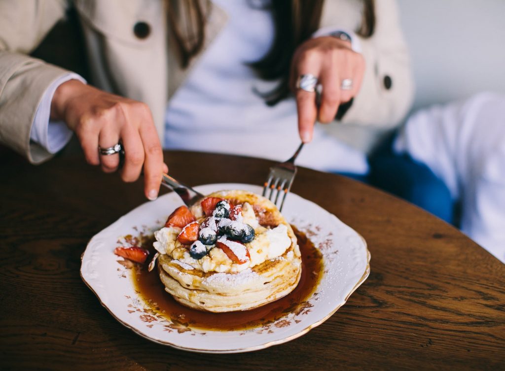 person eating pancakes with fresh fruits